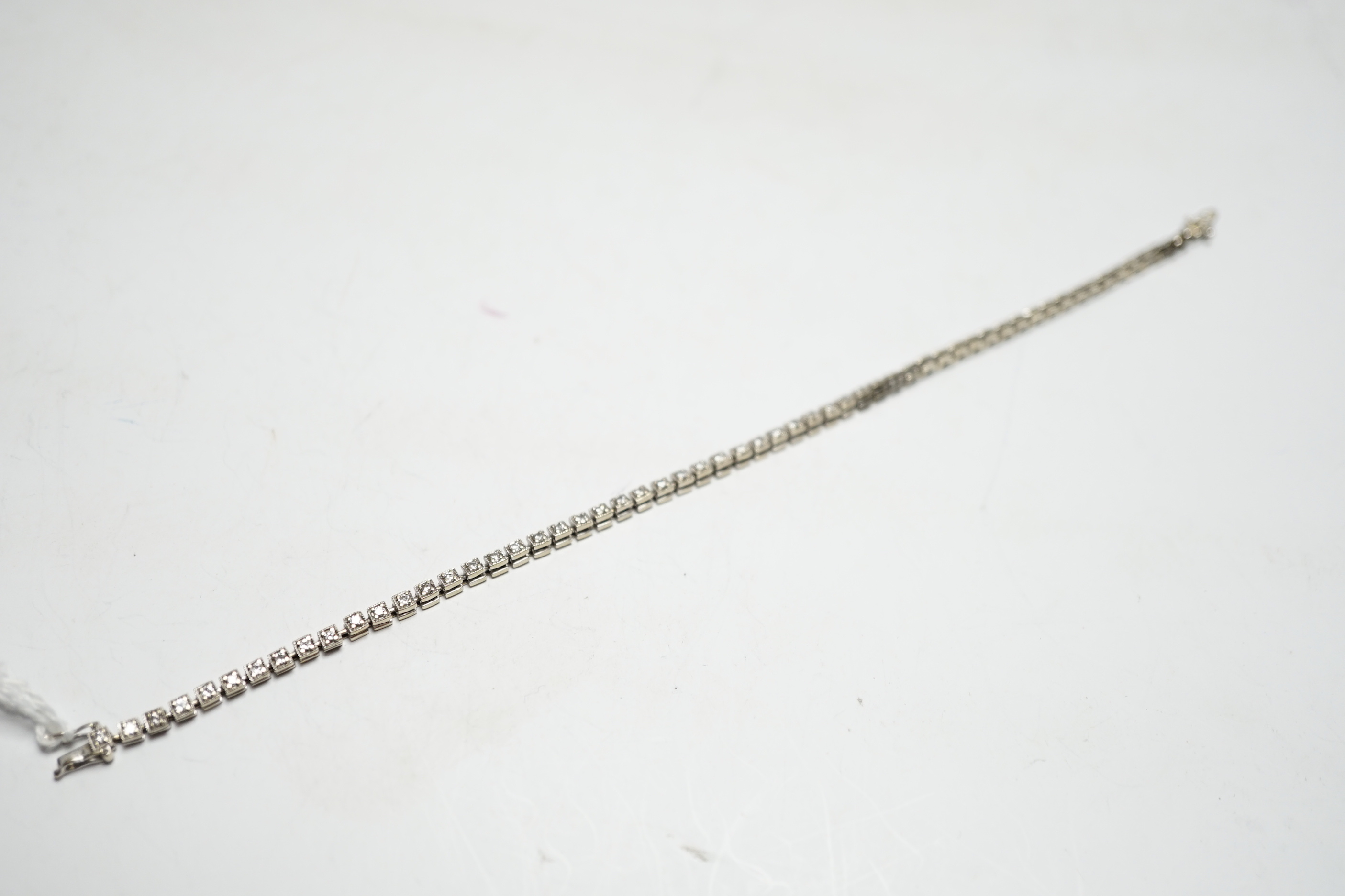 A 750 white metal and diamond line bracelet, set with sixty small stones, 20.8cm, gross weight 12 grams.
